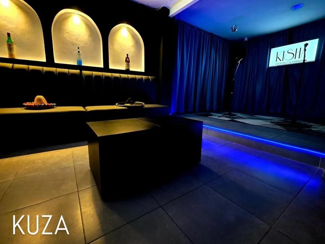 Sala privada KUZA de Kisha, con sofás, pantallas y escenario de karaoke
